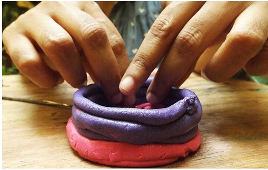 Closeup photo of hands molding brightly colored clay