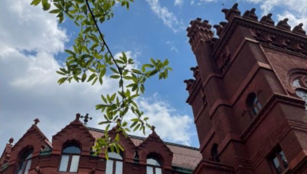 Photo of sky with roofline of Fisher Fine Arts Library and trees visible 