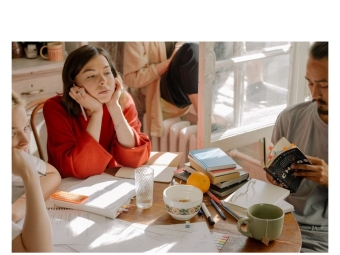 Students sitting around a table covered in books.